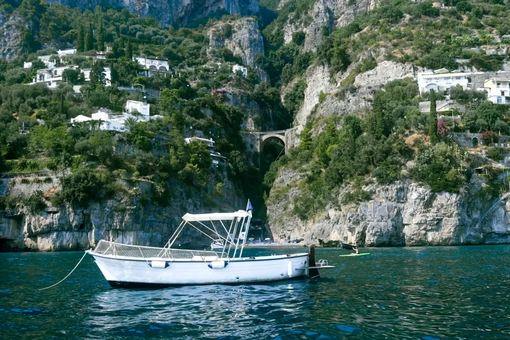 A white boat on the water below the cliffs of Capri