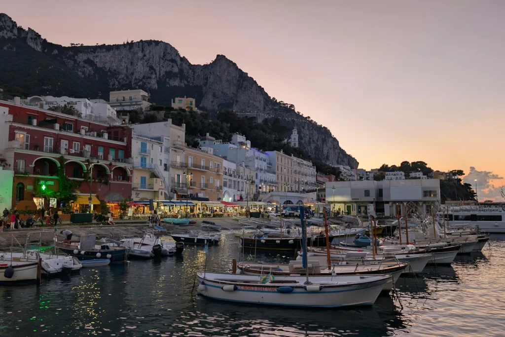 Boats moored in the harbour of Capri with the town lit at sunset