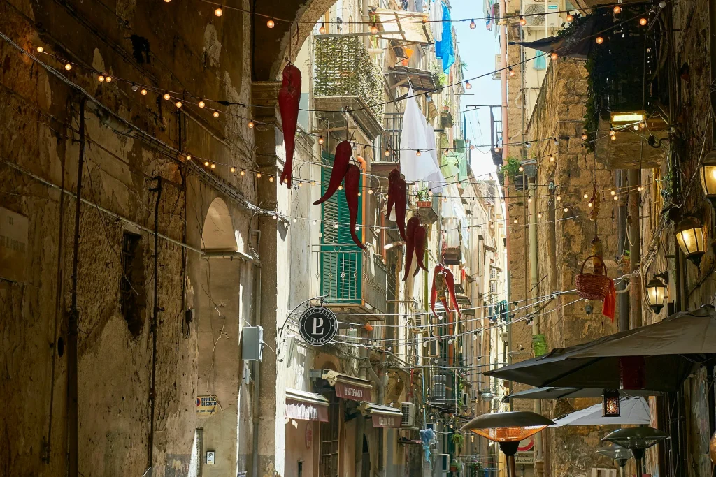 A narrow street in the historic centre of Naples, lined with small shops