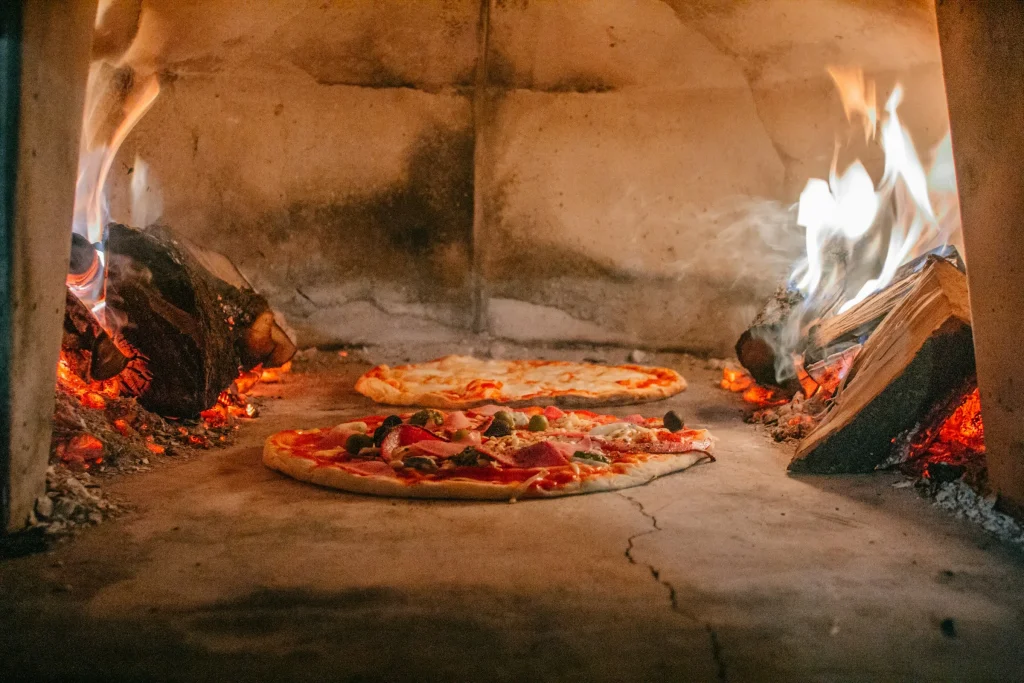 A pizza cooking in a wood fired stone oven in Naples