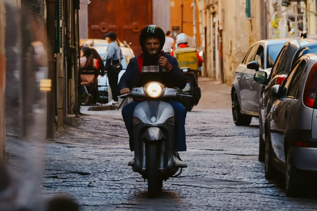 A scooter riding down a narrow cobbled street in the historic centre of Naples
