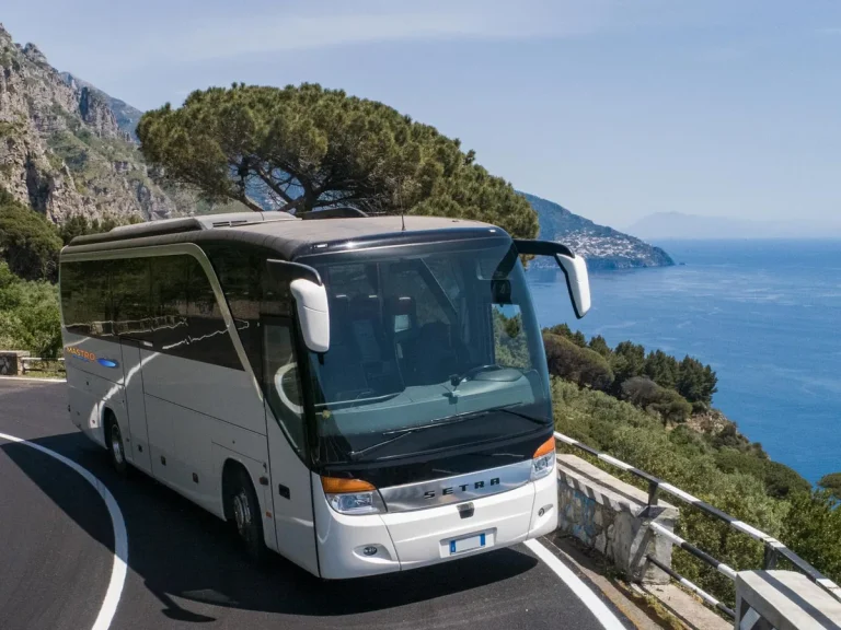 The company white touring coach seen from the front on the Amalfi Coast road