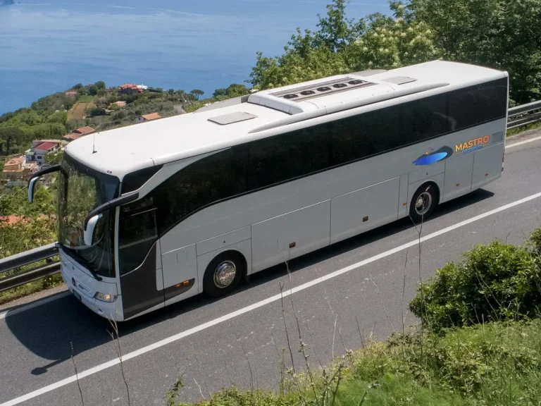 The company white full size touring coach seen from the side on the coast road