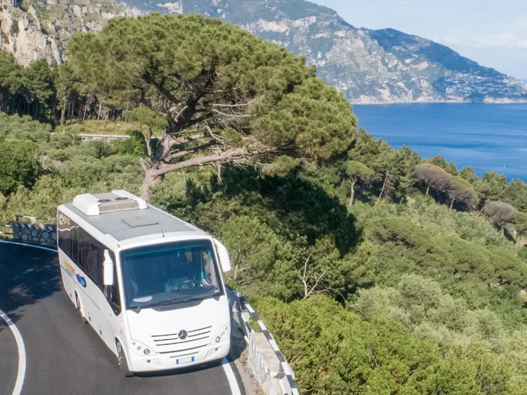 The company white medium coach on the Amalfi Coast road above the sea
