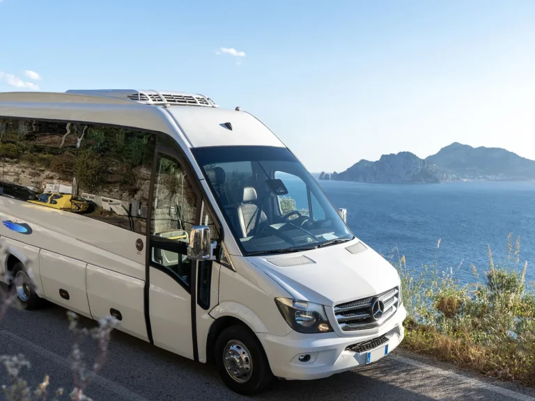 The company white Mercedes minibus parked on the coast road with the island of Capri behind