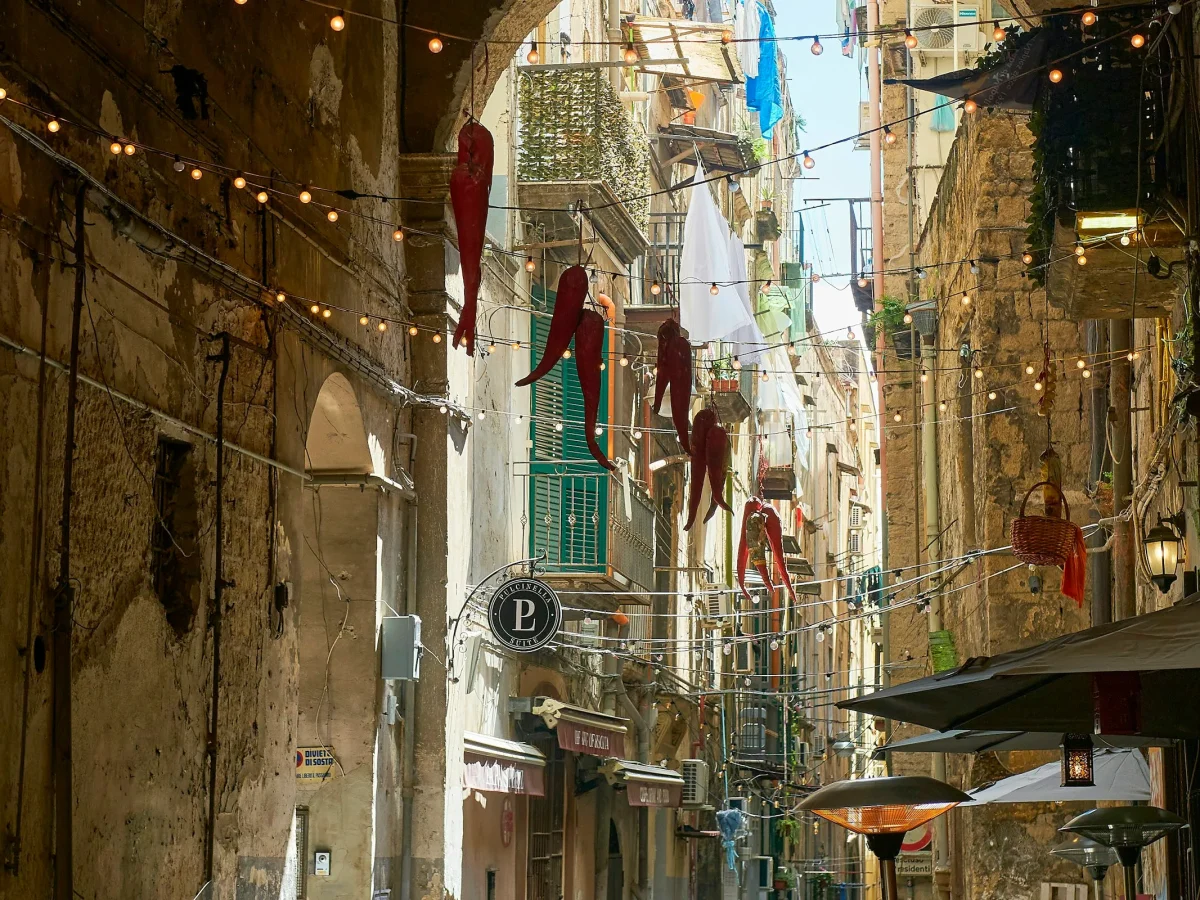 A narrow street in the historic centre of Naples, lined with small shops